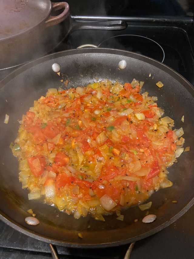 Tomatoes onions and other spices cooking in a pan